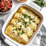 Close-up of green chili chicken enchiladas with melted cheese and cilantro in a white baking dish