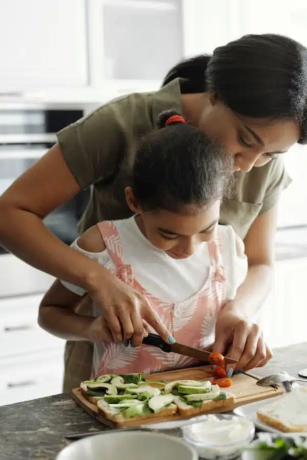 nancy-mccarthy-cooking-with-her-doughter Nancy McCarthy cooking with her daughter in a cozy home kitchen, preparing fresh veggie sandwiches — a heartwarming moment reflecting family values and hands-on learning.